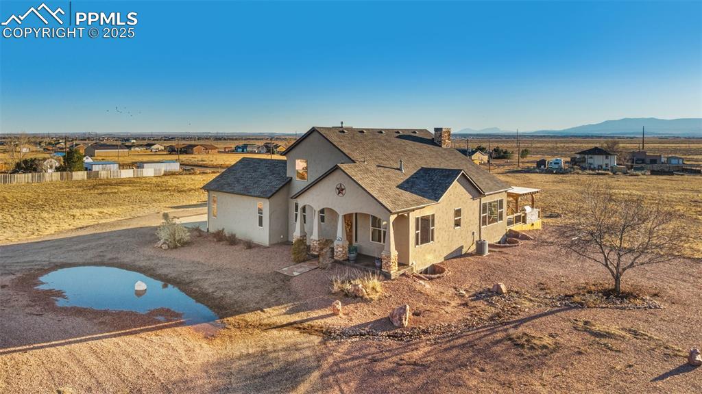 Image 43 of 49: View of front of house with roof with shingles, stucco siding, a mountain v