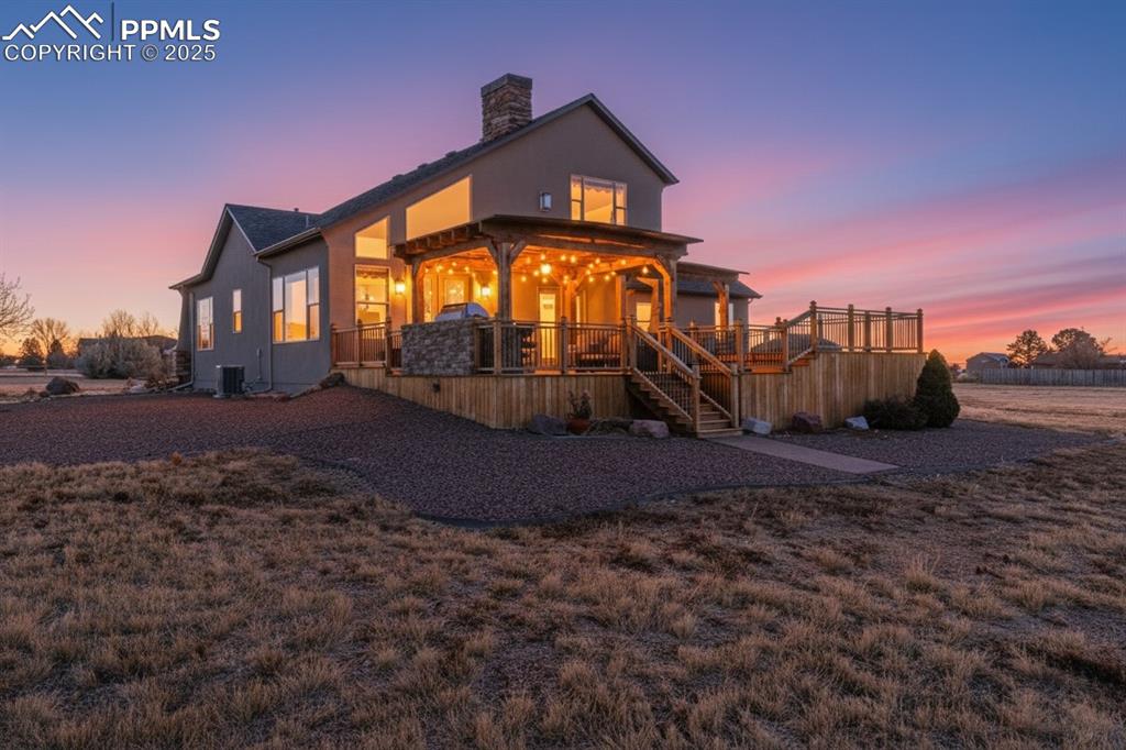 Image 5 of 49: Back of property at dusk with stairs, a chimney, and a wooden deck