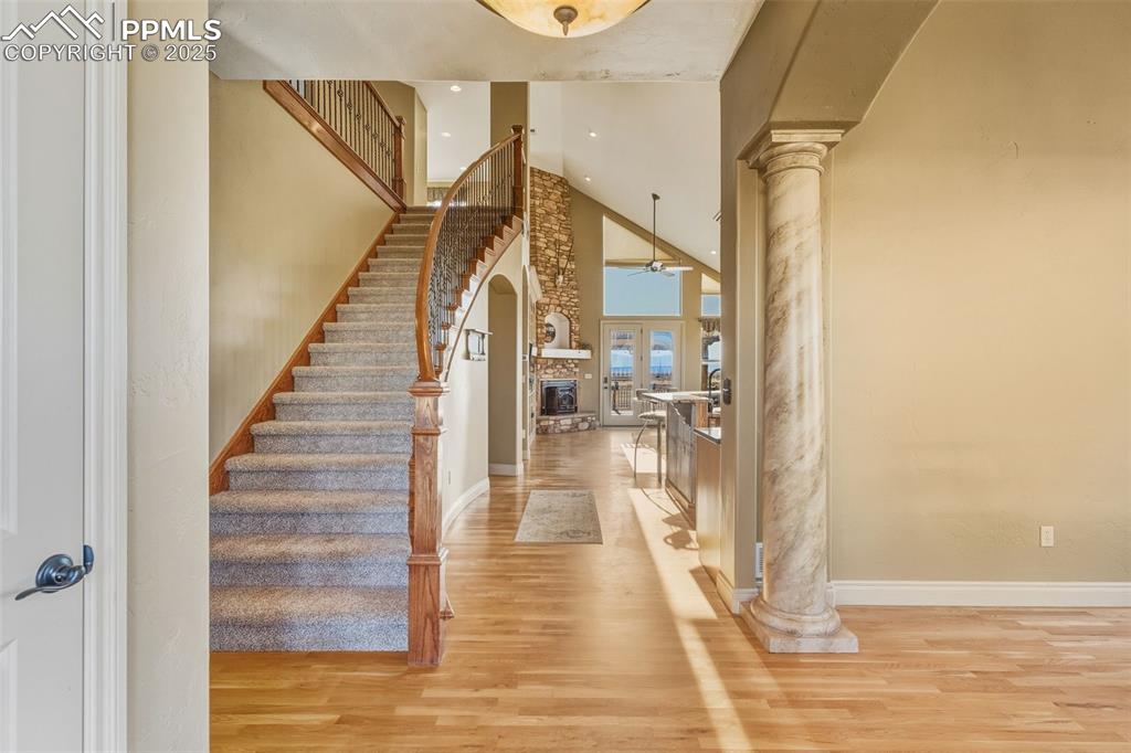 Image 7 of 49: Entryway with ornate columns, light wood-style floors, a fireplace, a high 
