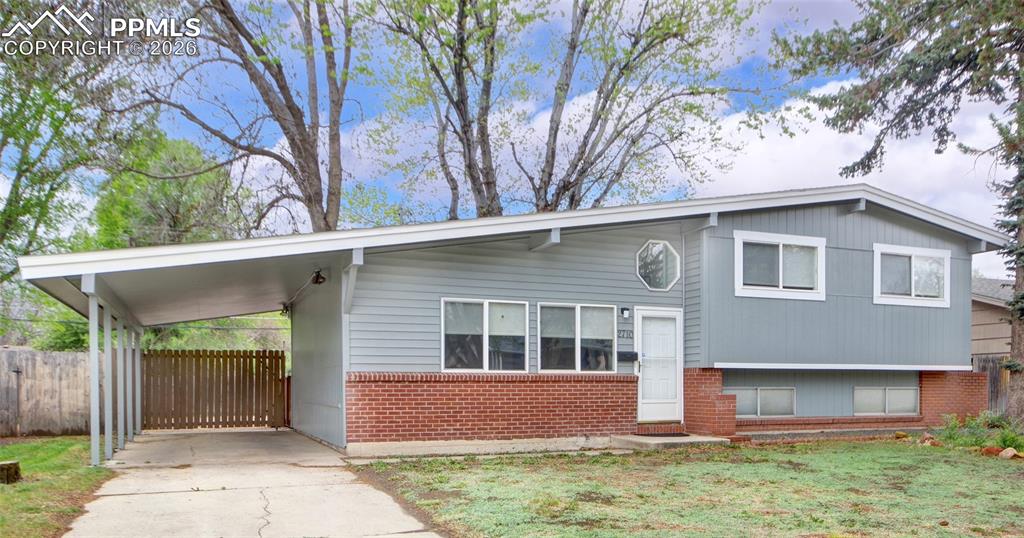 Caption: Split-level residence featuring gray siding and a brick foundation