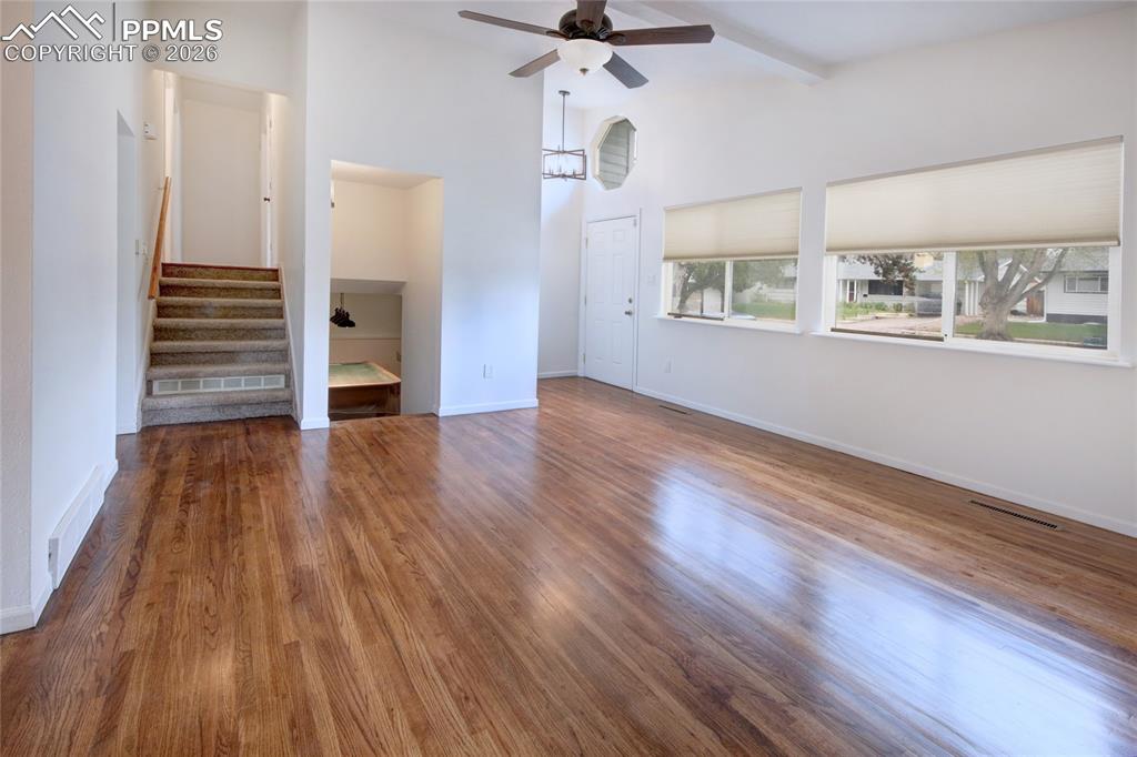 Image 10 of 27: Spacious main living area featuring wood-finish flooring, vaulted ceilings,