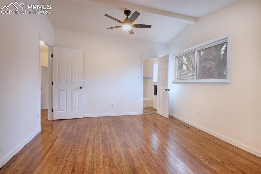 Image 11 of 27: Spacious master bedroom featuring wood-finish flooring, a vaulted ceiling, 