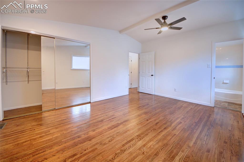 Image 12 of 27: Spacious master bedroom featuring wood-finish flooring, a vaulted ceiling, 