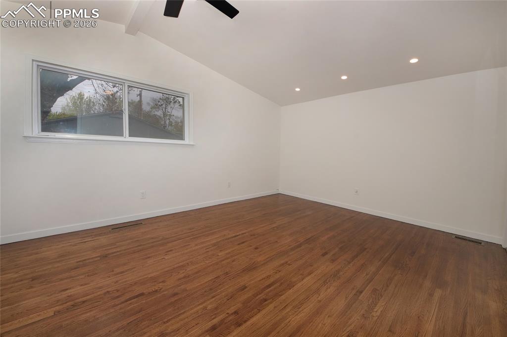 Image 13 of 27: Spacious master bedroom featuring wood-finish flooring, a vaulted ceiling, 