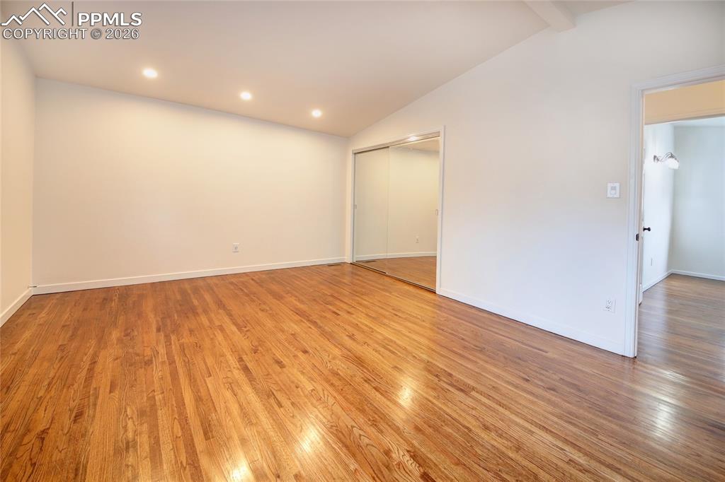 Image 14 of 27: Spacious master bedroom featuring wood-finish flooring, a vaulted ceiling, 