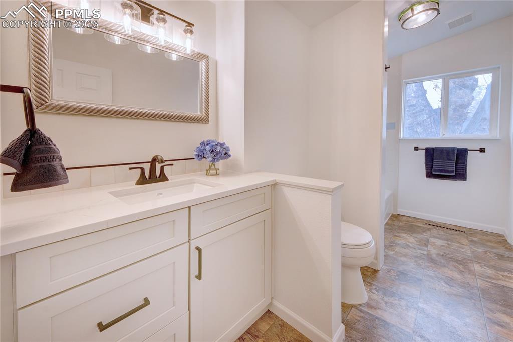 Image 15 of 27: White vanity with an integrated sink and black hardware