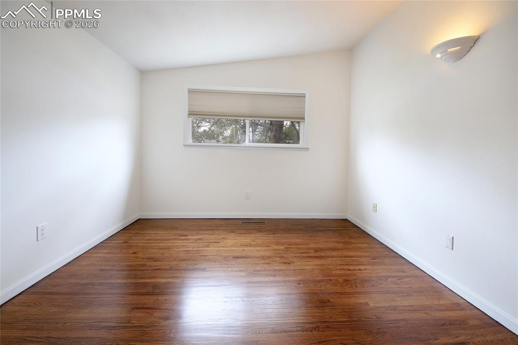 Image 16 of 27: Bright second bedroom featuring wood-finish flooring, white baseboards, and