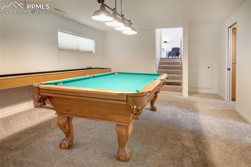Image 21 of 27: Recreation room with shuffleboard table featuring neutral-toned carpeting a