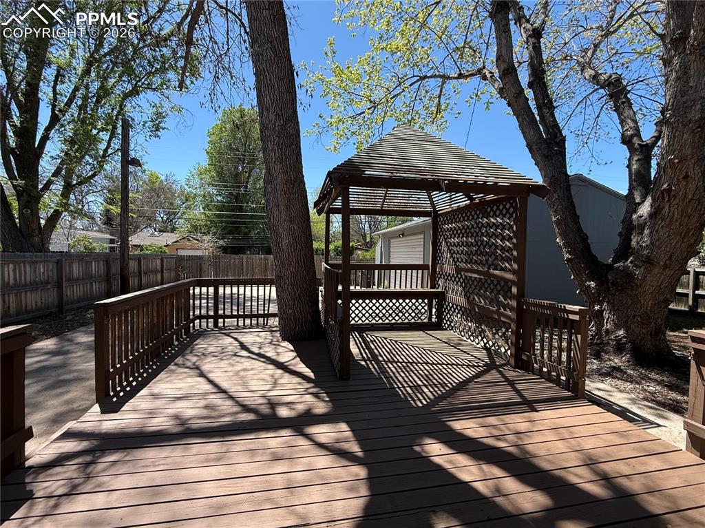 Image 23 of 27: Expansive wood-finish deck featuring a built-in gazebo with lattice details