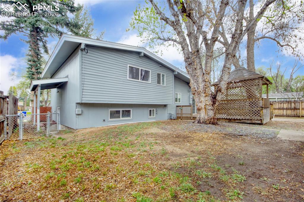 Image 24 of 27: Rear exterior featuring light blue siding, multiple windows, a covered entr