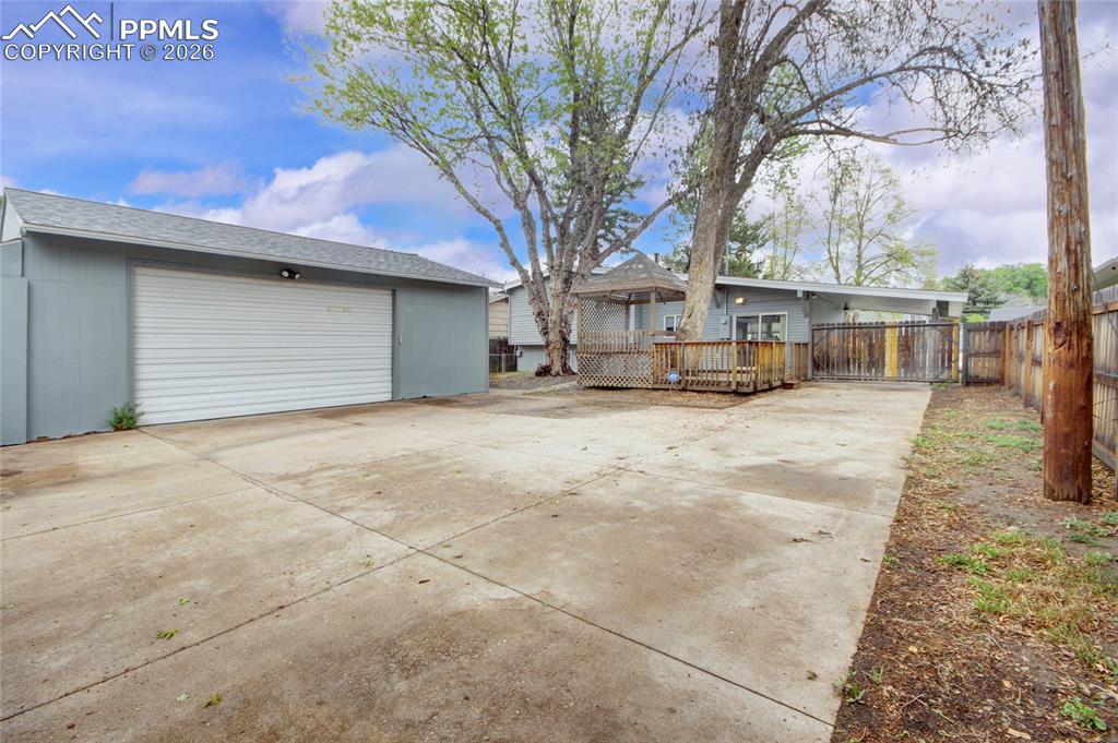 Image 26 of 27: Spacious concrete driveway featuring a detached garage with a white roll-up