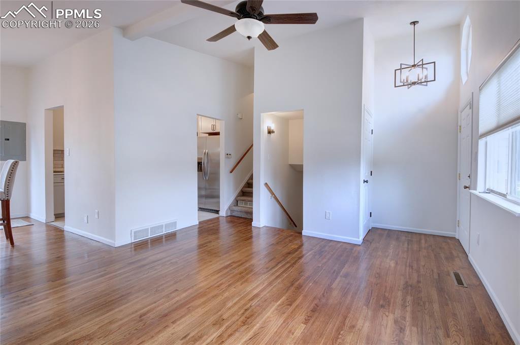 Image 3 of 27: Spacious room featuring wood-finish flooring, vaulted ceilings, and a moder