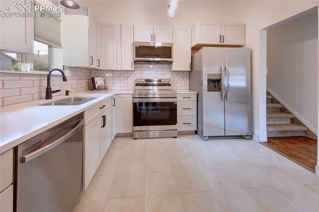 Image 6 of 27: Modern kitchen featuring light-toned cabinetry, light countertops, subway t