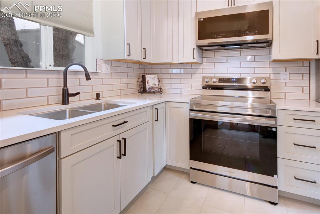 Image 8 of 27: Kitchen featuring white shaker cabinetry, white countertops, stainless stee