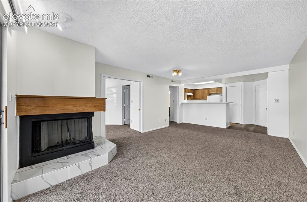 Image 10 of 22: Living area with a corner fireplace, wood mantel, and a tiled hearth