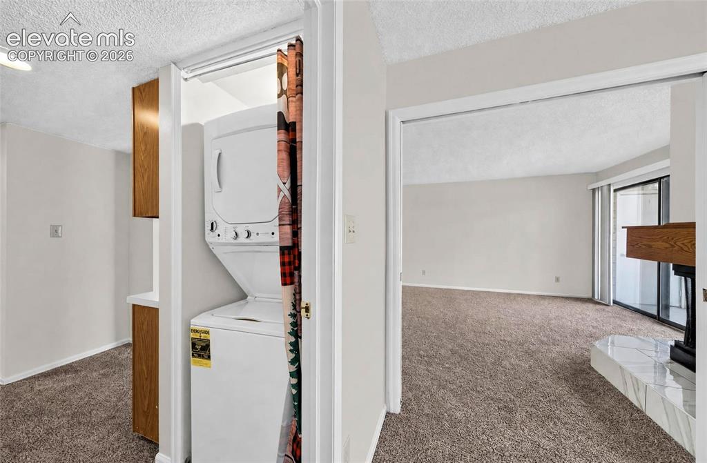 Image 16 of 22: Stacked washer and dryer unit, wood-finish cabinetry, sliding glass doors, 
