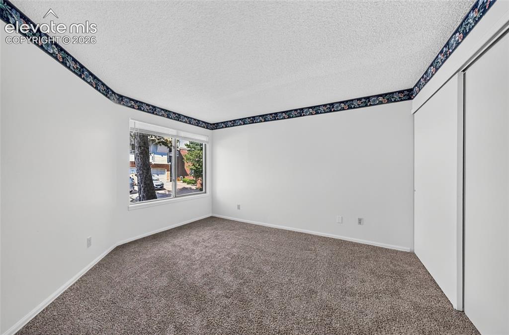 Image 18 of 22: Wall-to-wall carpeting, dual sliding closet doors, and window with blinds