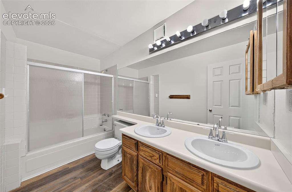 Image 20 of 22: Dual vanity with integrated sinks, wood-finish cabinetry, a full-width mirr