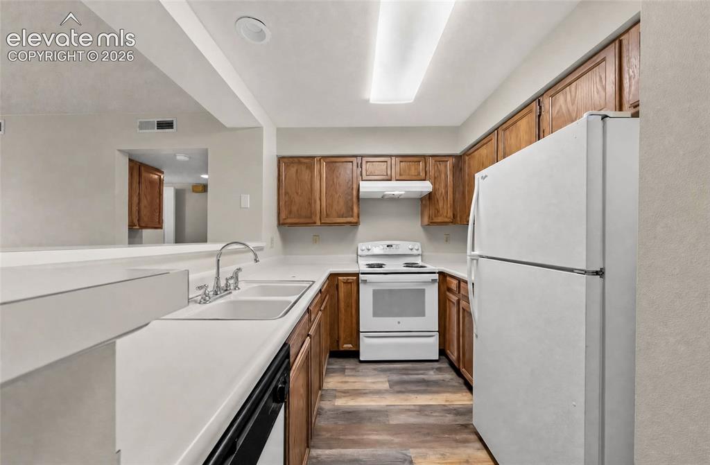 Image 4 of 22: Kitchen featuring wood-finish cabinetry, white appliances, dual basin sink,