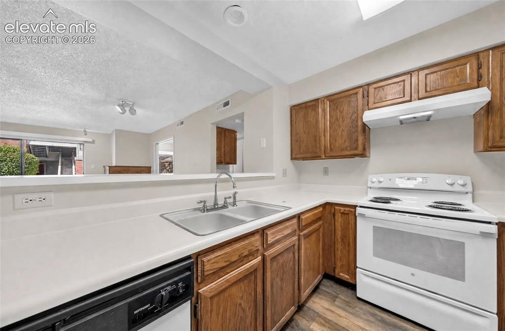 Image 5 of 22: Kitchen with wood-finish cabinetry, white countertops, a double basin sink