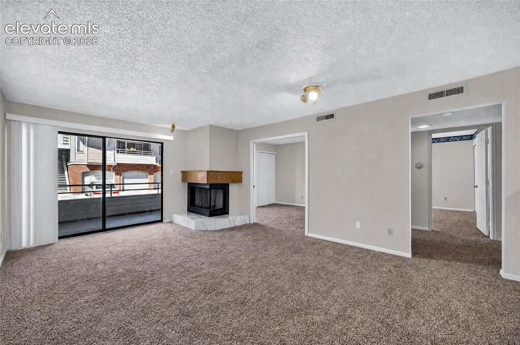 Image 9 of 22: Wall-to-wall carpeting, corner fireplace with a wood mantel and marble-fini