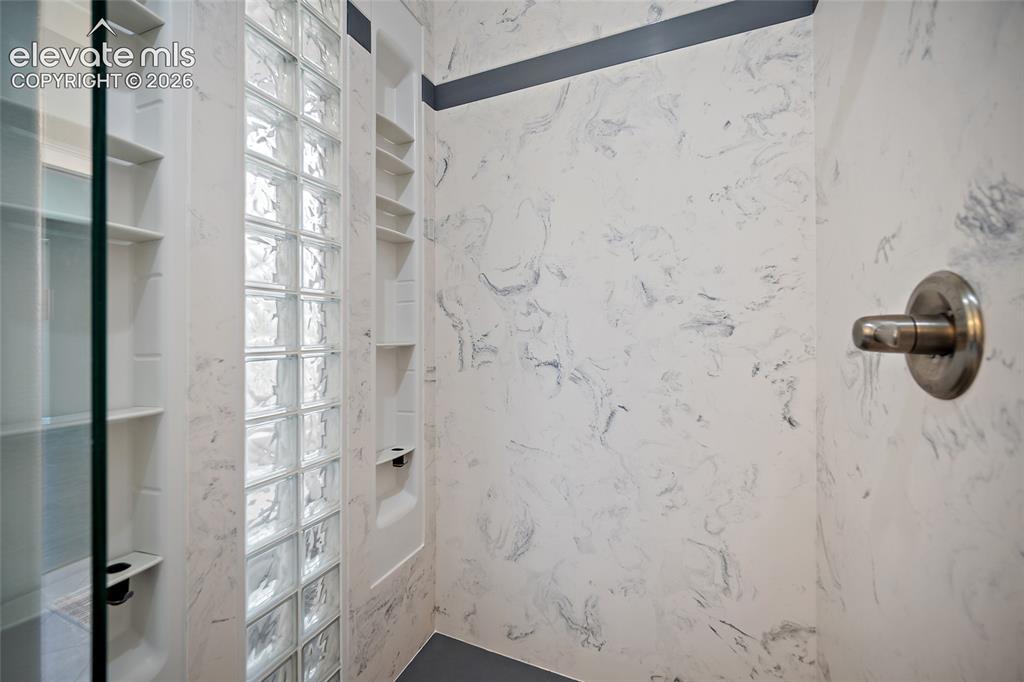 Image 34 of 50: Custom shower with shelves and private glass that allows light to enter.