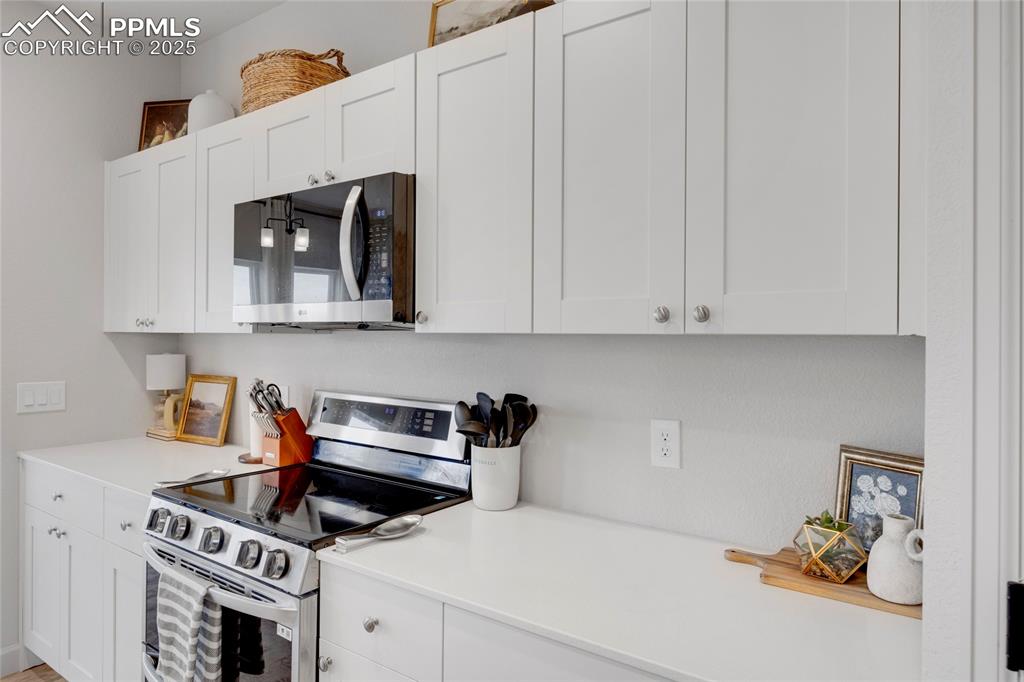 Image 10 of 37: Kitchen with appliances with stainless steel finishes and white cabinets