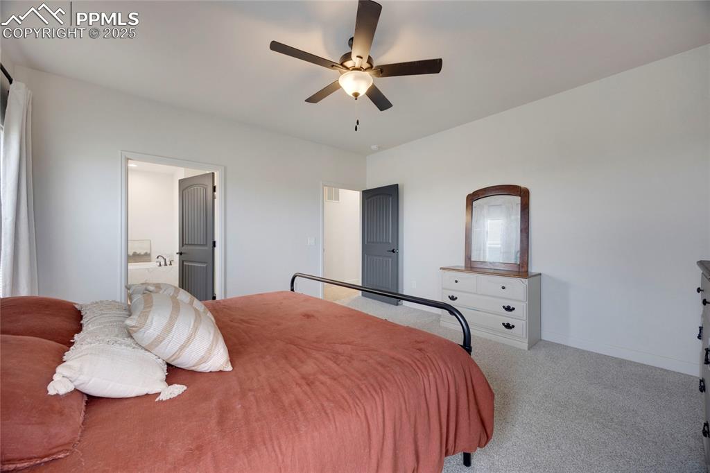Image 20 of 37: Bedroom with carpet, ensuite bath, and a ceiling fan