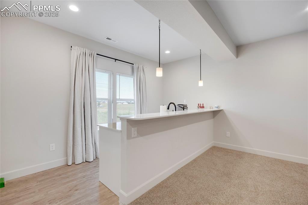 Image 25 of 37: Bar with decorative light fixtures, recessed lighting, light stone countert