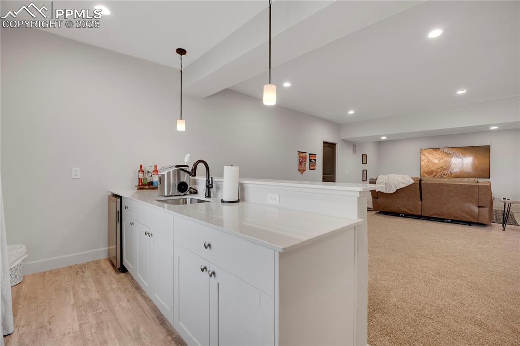 Image 26 of 37: Kitchen with a peninsula, white cabinets, recessed lighting, pendant lighti