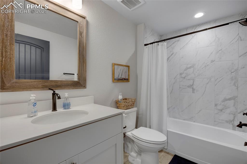 Image 29 of 37: Bathroom featuring shower / bath combination with curtain, vanity, and a te