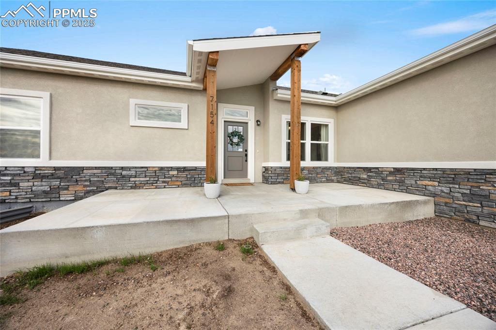 Image 3 of 37: Entrance to property with stucco siding and stone siding