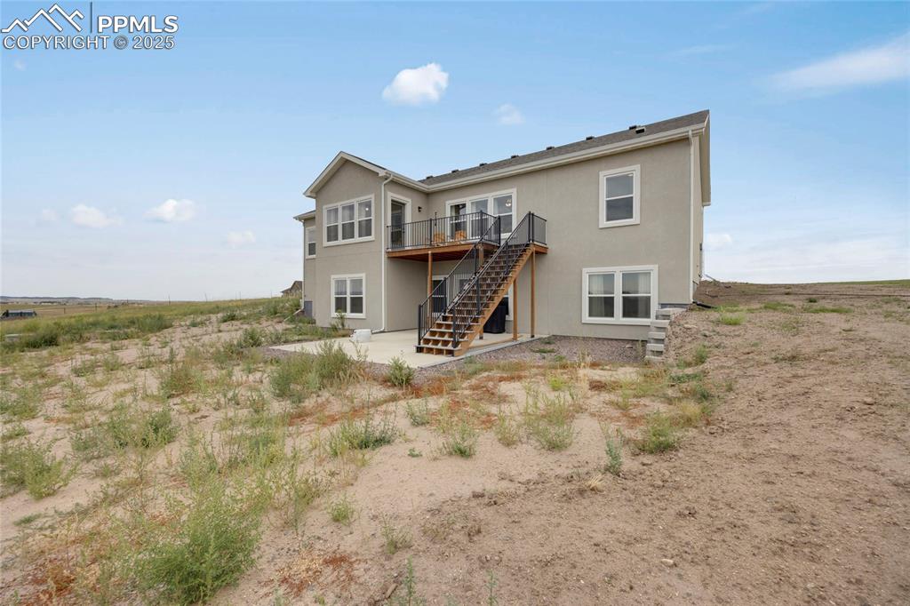 Image 35 of 37: Back of property with stairs, stucco siding, a deck, and a patio