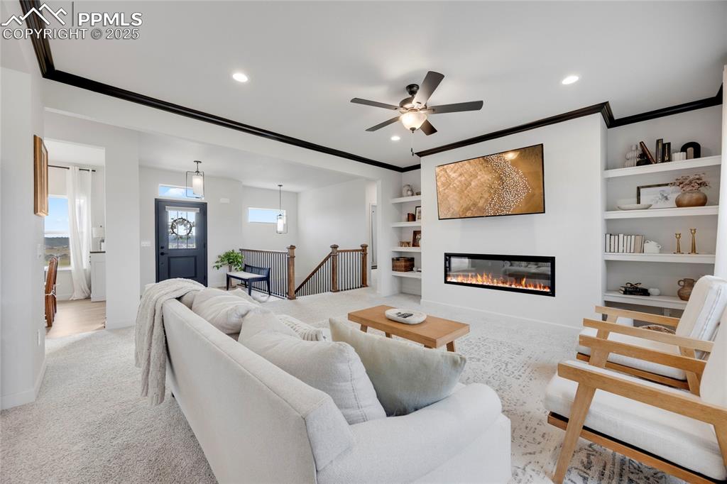 Image 6 of 37: Living room with light carpet, ornamental molding, built in features, a gla