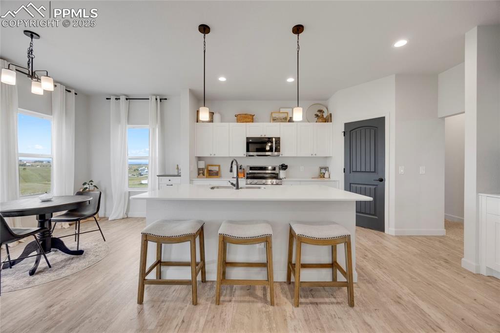 Image 7 of 37: Kitchen featuring pendant lighting, white cabinets, a breakfast bar area, l