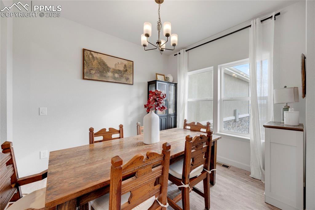 Image 9 of 37: Dining area with light wood-style flooring and a chandelier