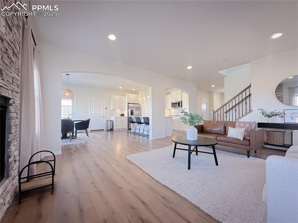 Image 16 of 42: Living area featuring arched walkways, stairway, light wood-style floors, a