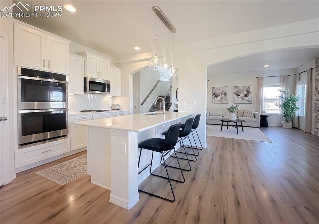 Image 17 of 42: Kitchen featuring decorative light fixtures, arched walkways, a kitchen bre
