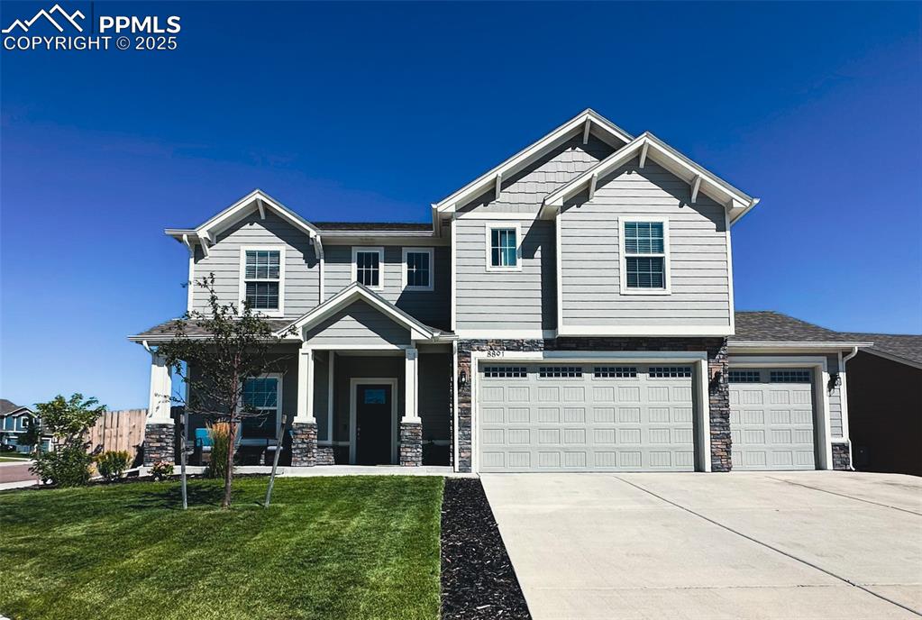 Image 2 of 42: Craftsman inspired home with stone siding, covered porch, driveway, a front