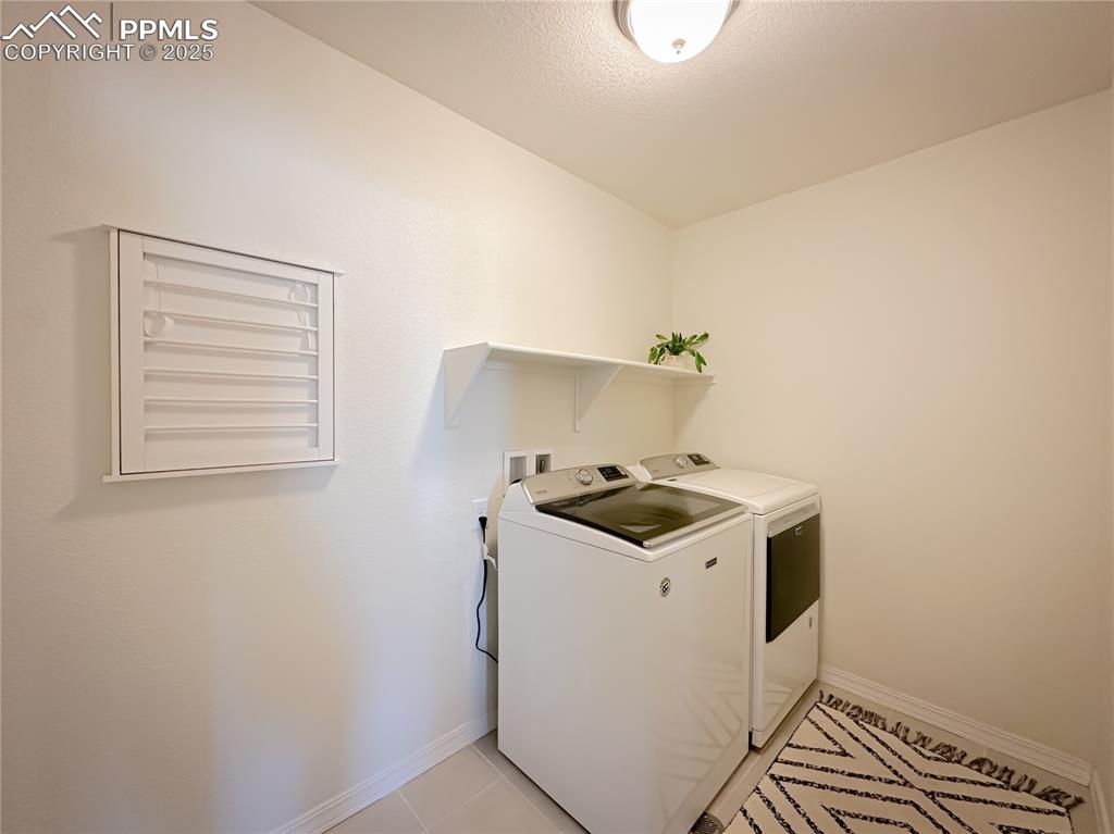 Image 24 of 42: Washroom with washing machine and dryer, light tile patterned floors, and a