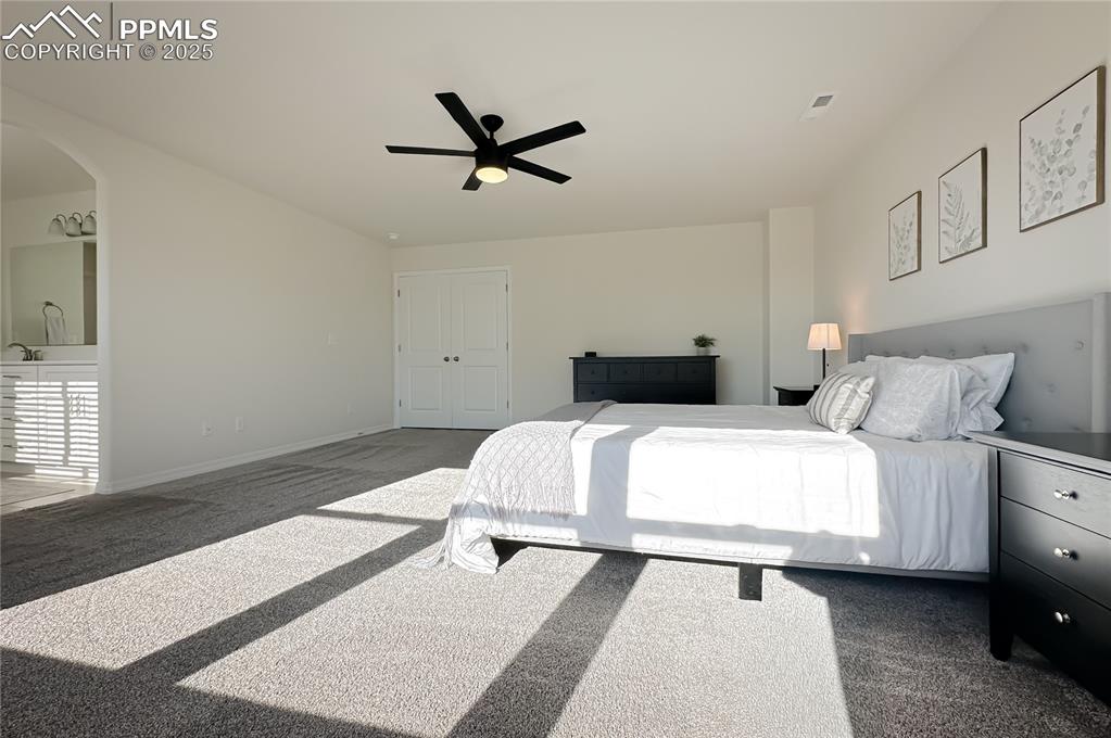 Image 26 of 42: Bedroom with dark carpet, ceiling fan, and arched walkways