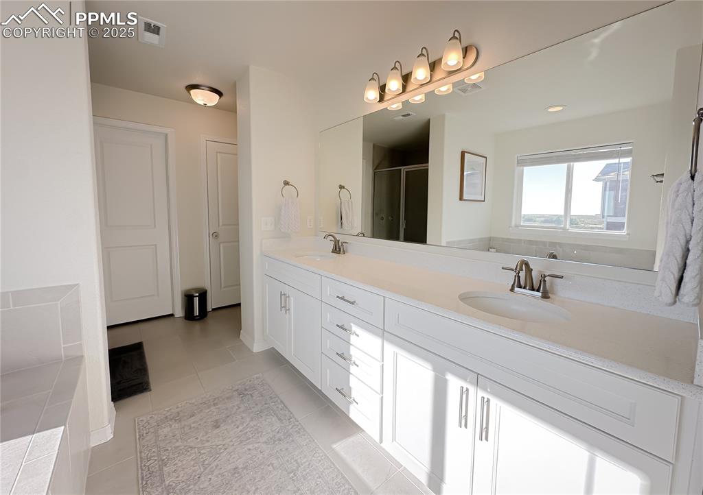 Image 27 of 42: Bathroom featuring double vanity, a stall shower, and light tile patterned