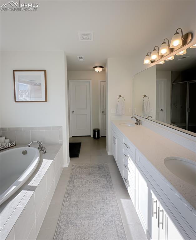 Image 28 of 42: Bathroom featuring double vanity, a bath, a shower stall, and light tile pa