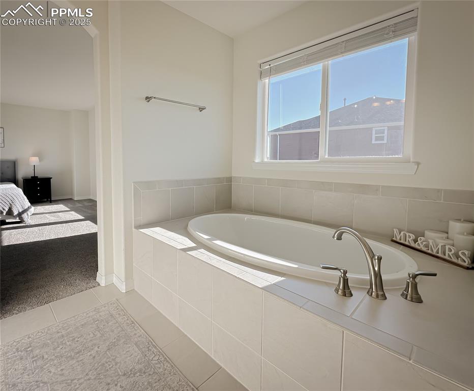 Image 29 of 42: Full bath featuring a garden tub, light tile patterned floors, and ensuite