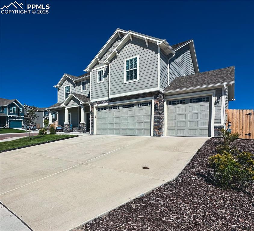 Image 3 of 42: Craftsman-style house with stone siding, concrete driveway, a porch, and an