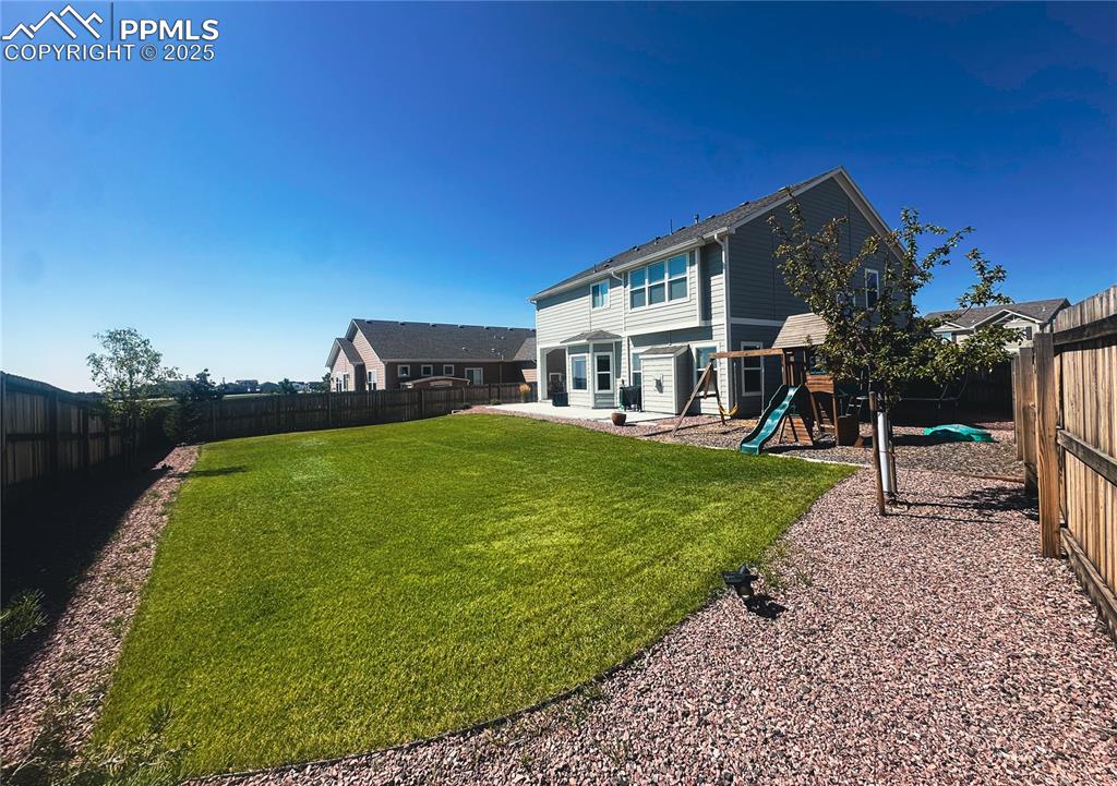 Image 39 of 42: Back of property with a fenced backyard, a patio area, and a playground