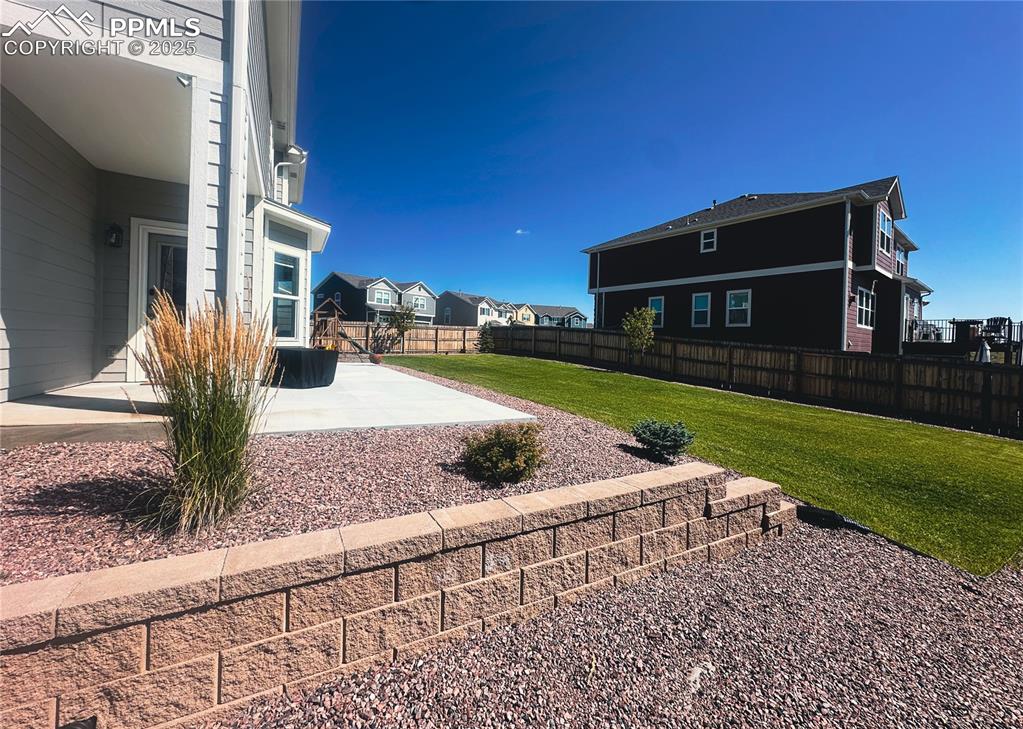 Image 41 of 42: Fenced backyard with a patio and a residential view