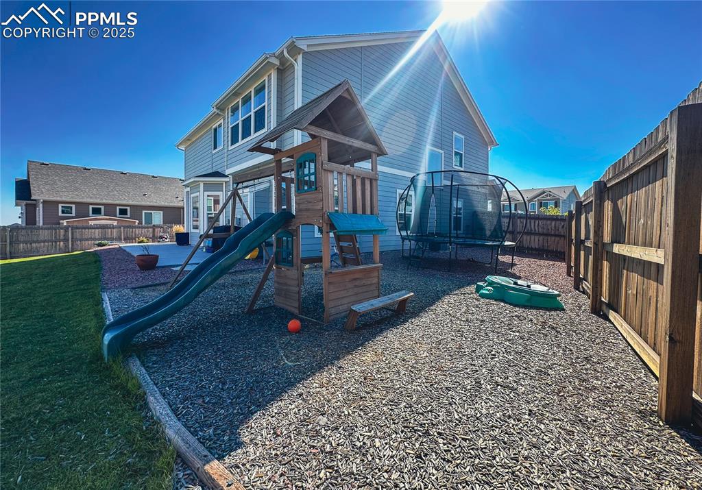 Image 42 of 42: View of jungle gym featuring a trampoline and a fenced backyard