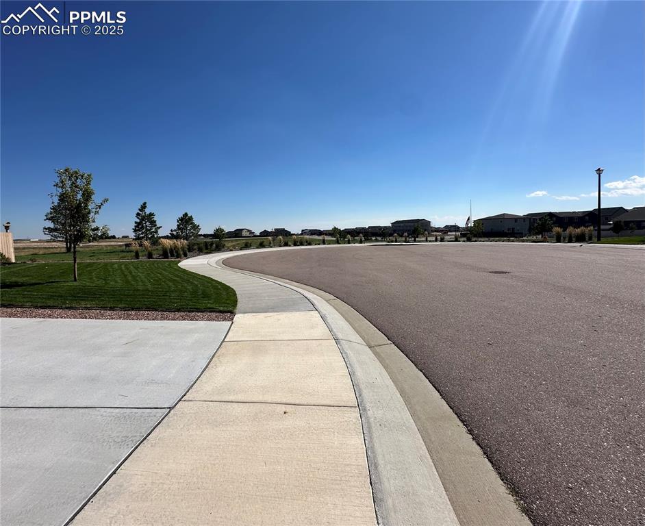 Image 6 of 42: View of asphalt road with sidewalks, street lights, and curbs