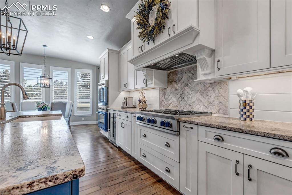 Image 24 of 50: Two tone kitchen featuring dual tone cabinets, a center island with sink, a